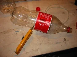 Using the utility knife, cut one bottle just below the label line.